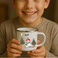Kind hält weiße Emaille Kindertasse mit silbernem Rand – personalisierte Tasse mit Namen und süßem Motiv